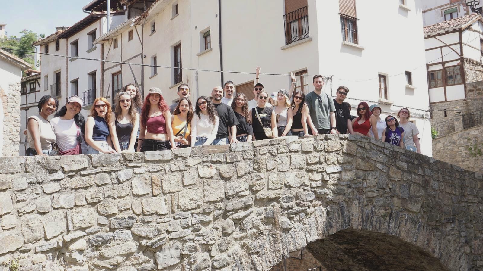 Een groep jongeren poseert op een brug in een Spaans dorp