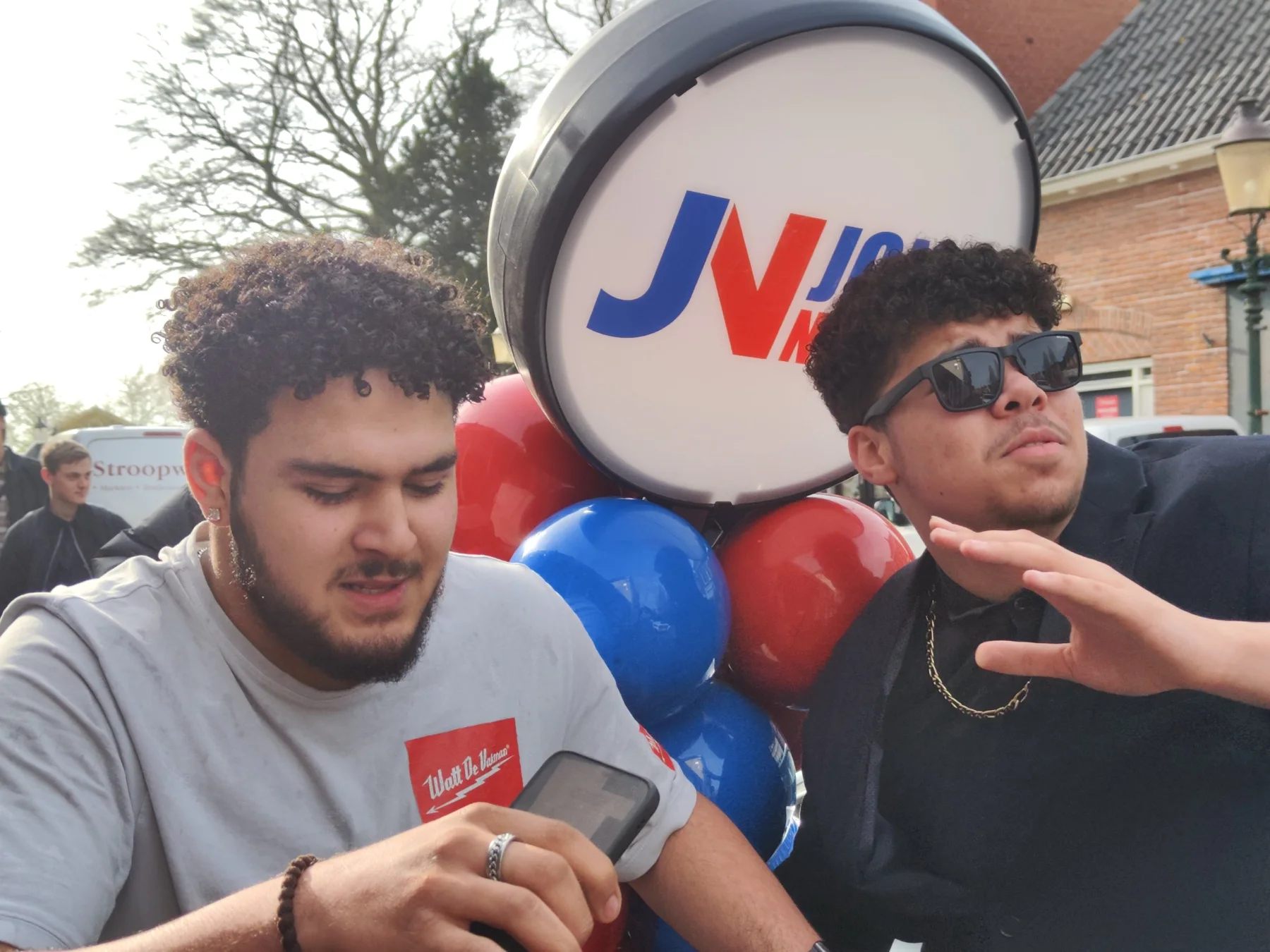 Twee jonge mannen bij een lichtbak met het logo van Jong Noord en rode en blauwe ballonnen
