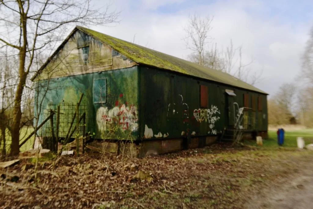 Het vervallen groene gebouw in het Tuikwerderrakbos, met graffiti op de wanden en mos op het dak
